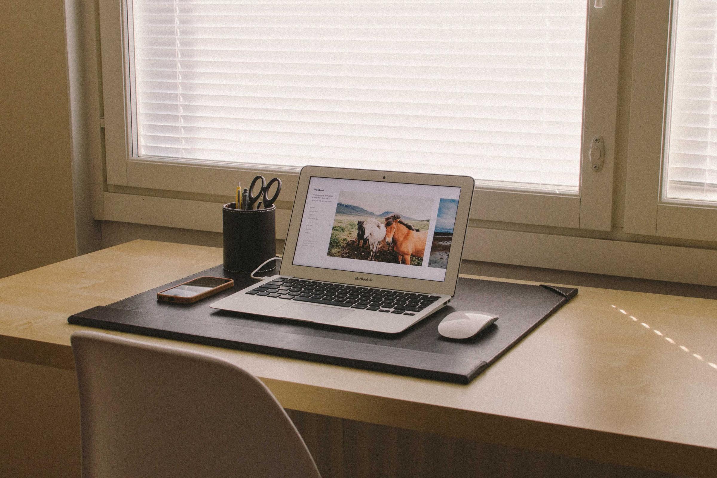 窓辺のデスクとノートPC。株式会社Ficusの制作の現場。